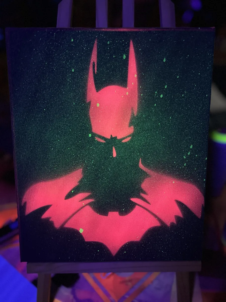 Neon pink caped figure in a green speckled night, under blacklight