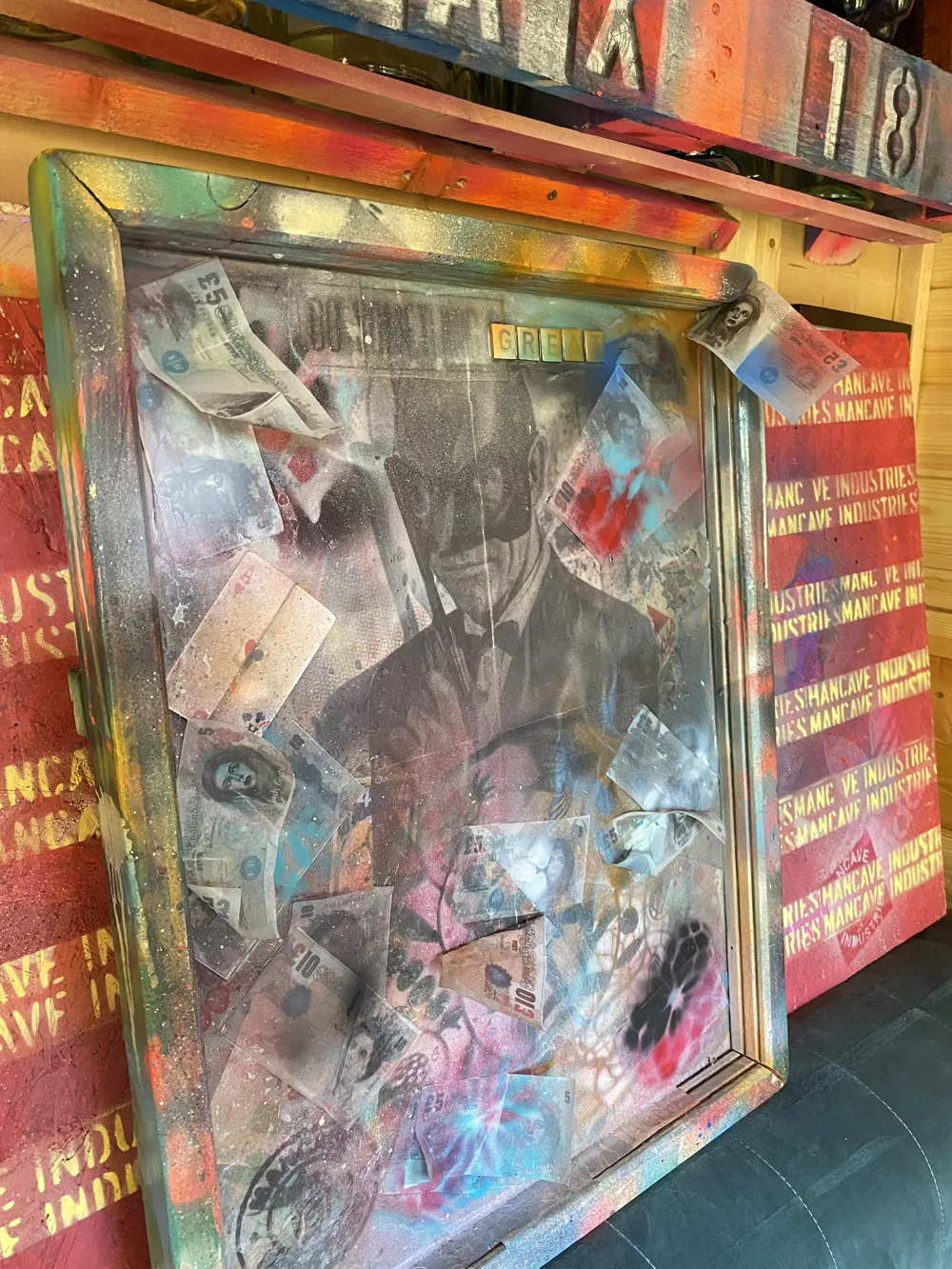 Greed: framed mixed-media piece with a masked figure surrounded by banknotes