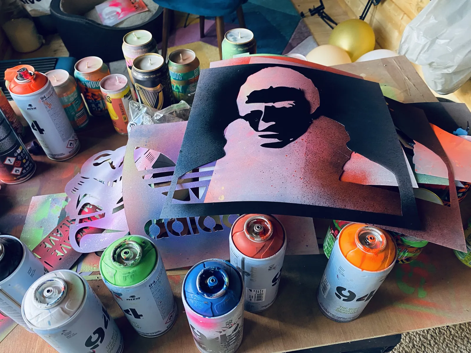 The spray bench: stencils, paint cans and a row of freshly poured can candles