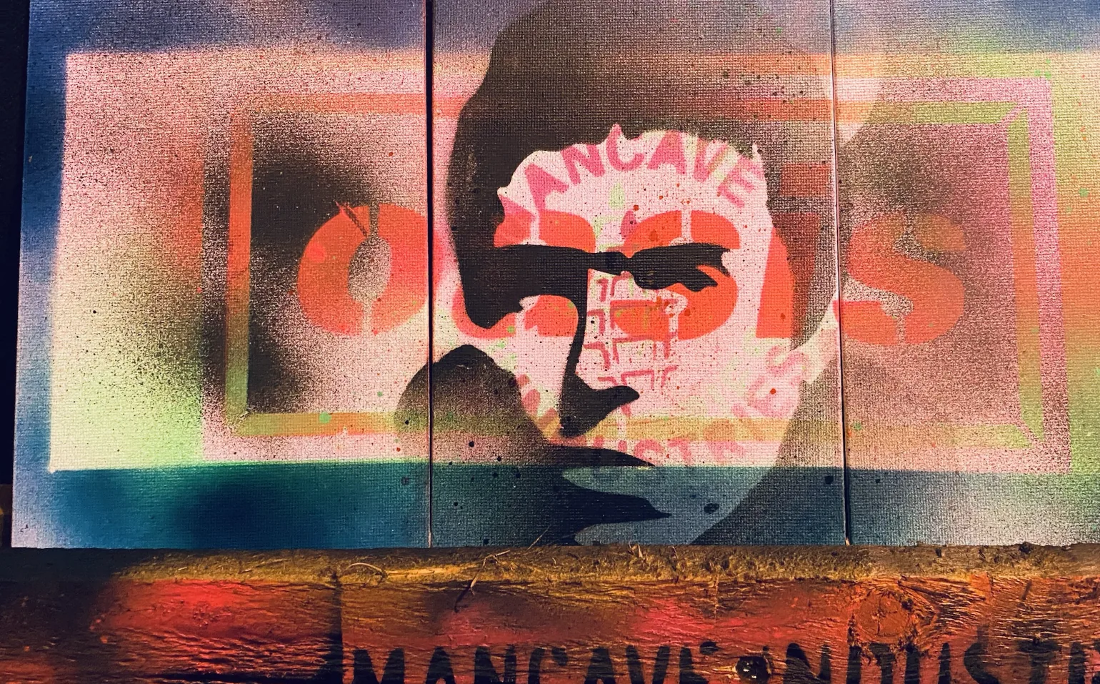 Triptych in daylight: a stencilled portrait over block lettering across three canvases