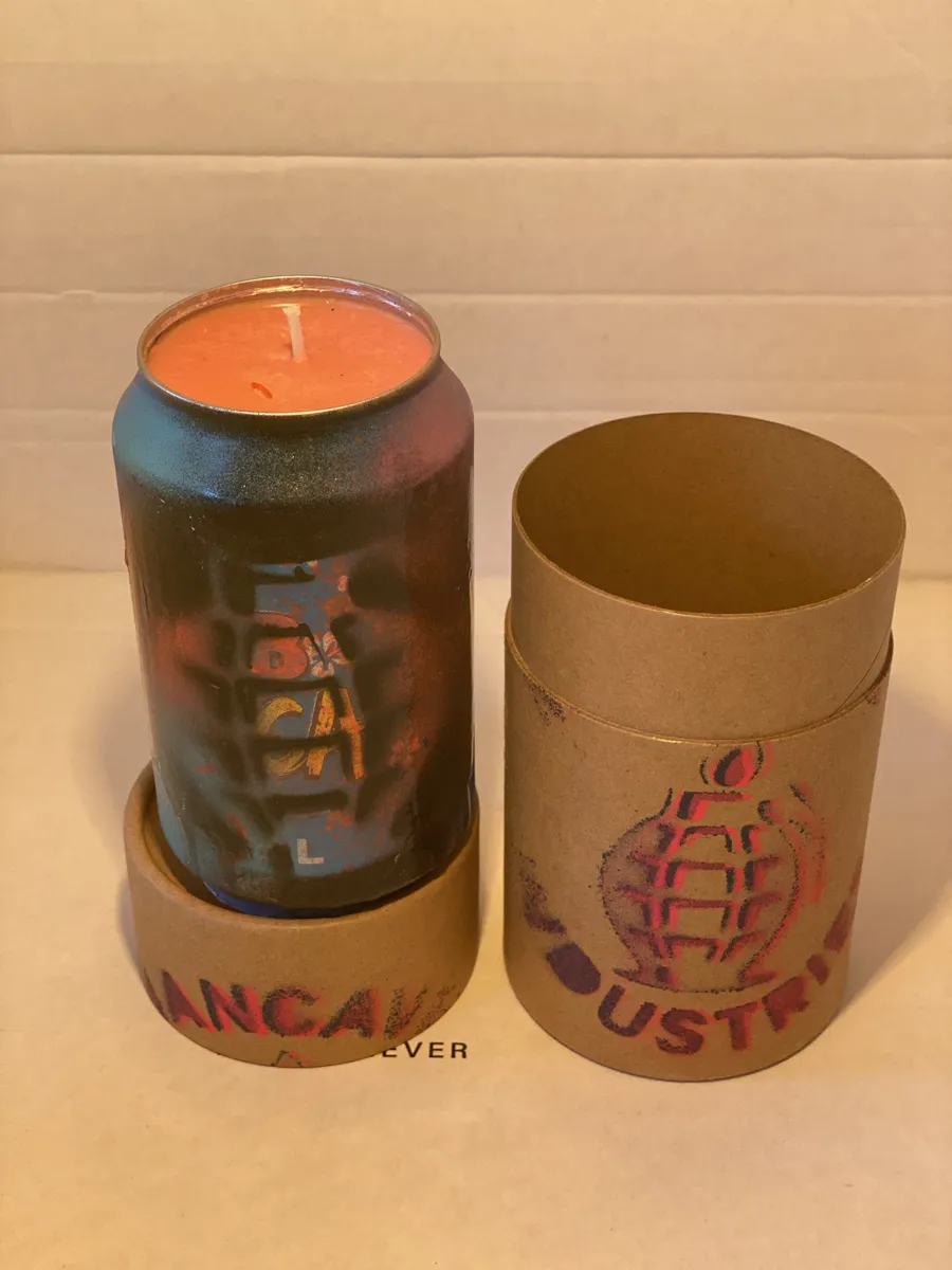 Blue and rust sprayed can candle with a grenade stencil, shown sitting in its open tube