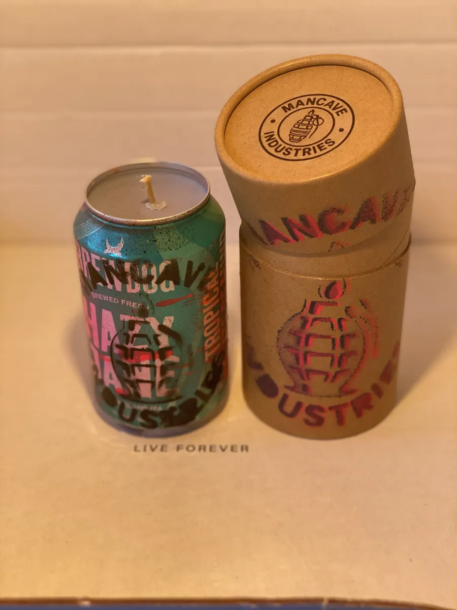 Teal can candle with Mancave Industries grenade stencil beside its kraft tube