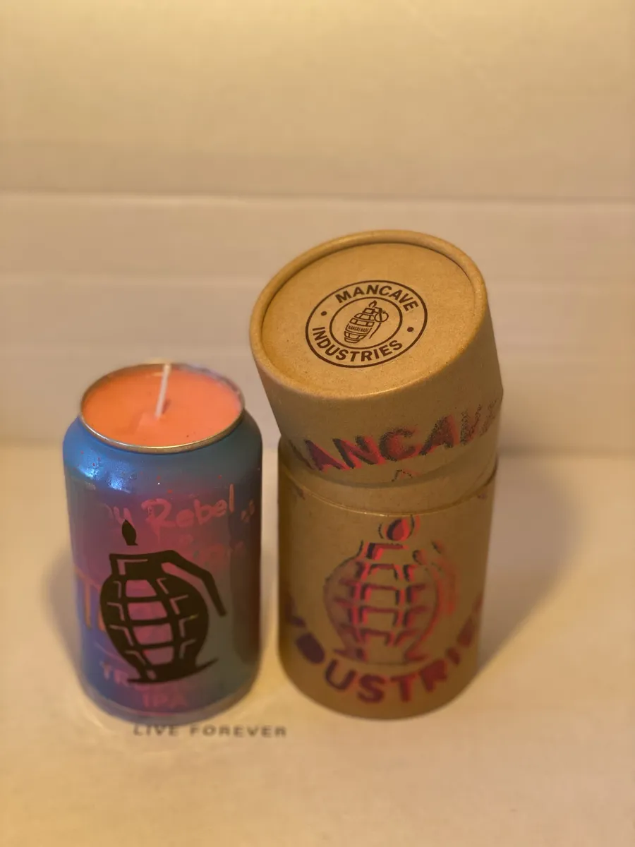 Purple-to-blue fade can candle with a black grenade stencil, beside its kraft tube